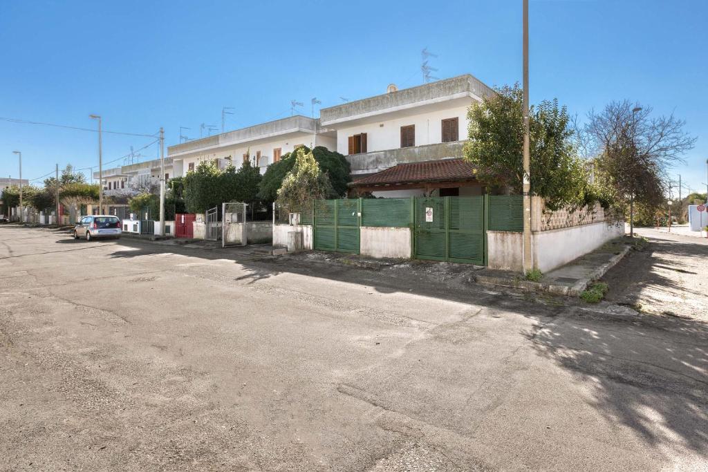 an empty street next to a building with a green fence at Complesso Pergolesi by BarbarHouse in Torre dell'Orso