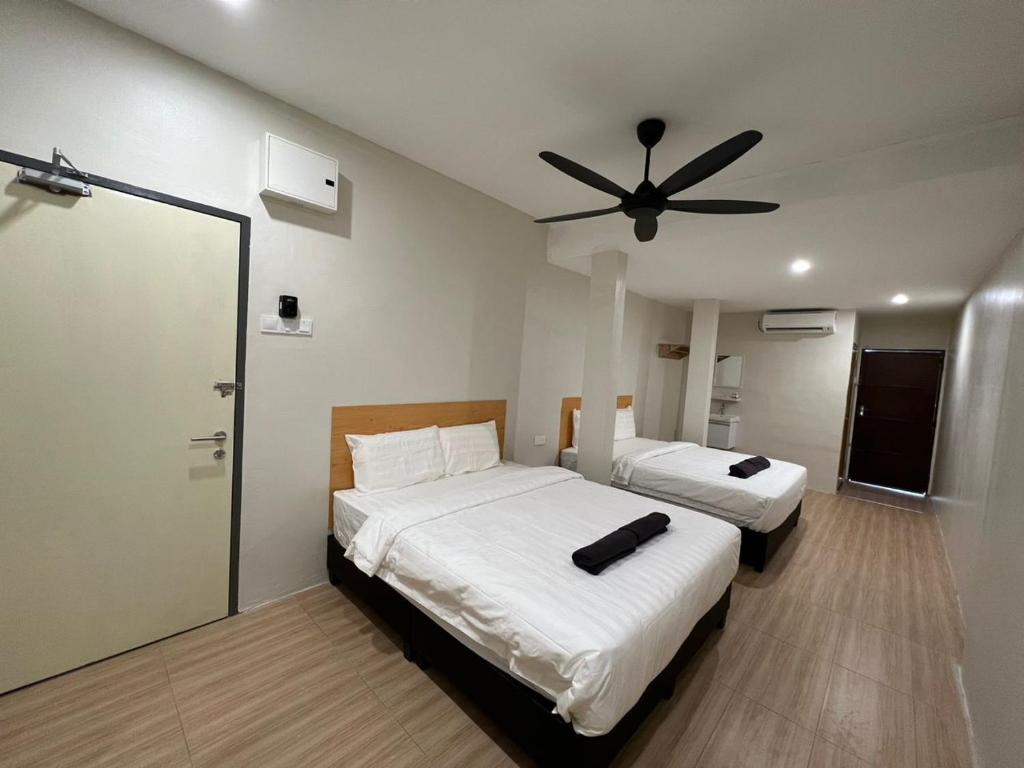 a bedroom with two beds and a ceiling fan at Homestay Suria in Kuala Kangsar