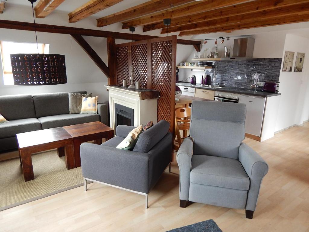 ein Wohnzimmer mit einem Sofa und Stühlen sowie eine Küche in der Unterkunft LANDHAUS LAAVE FERIENWOHNUNG 