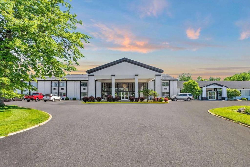 Un gran edificio blanco con coches aparcados en un estacionamiento. en Days Inn by Wyndham Erie, en Erie