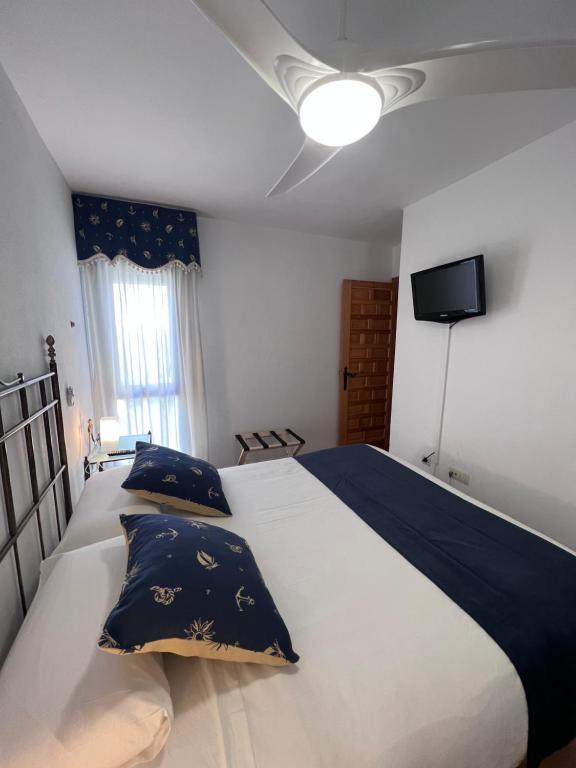 a bedroom with a large white bed with blue pillows at Apartamento Zahara in Zahara de los Atunes