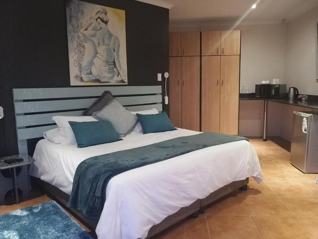una camera da letto con un grande letto bianco con cuscini blu di Cowrie Lodge at Cove Rock Country Estate a East London