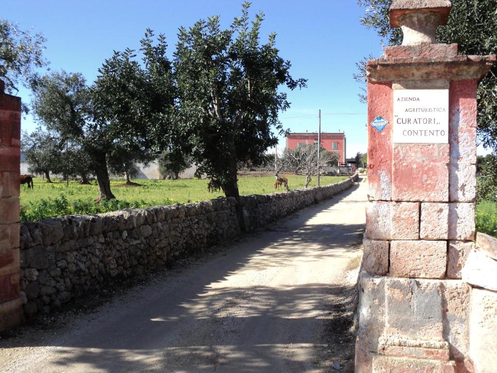 una pared de piedra con un letrero al costado de una carretera en Masseria Curatori, en Monopoli