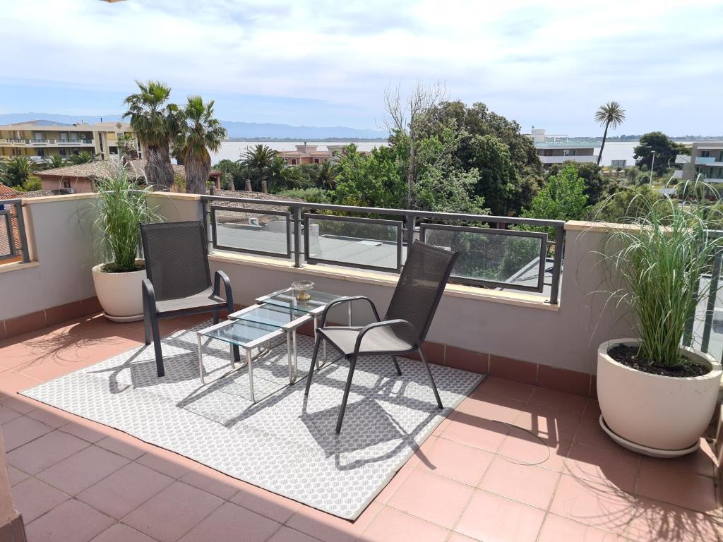 a balcony with a glass table and chairs on a roof at Penthouse genneruxi in Cagliari