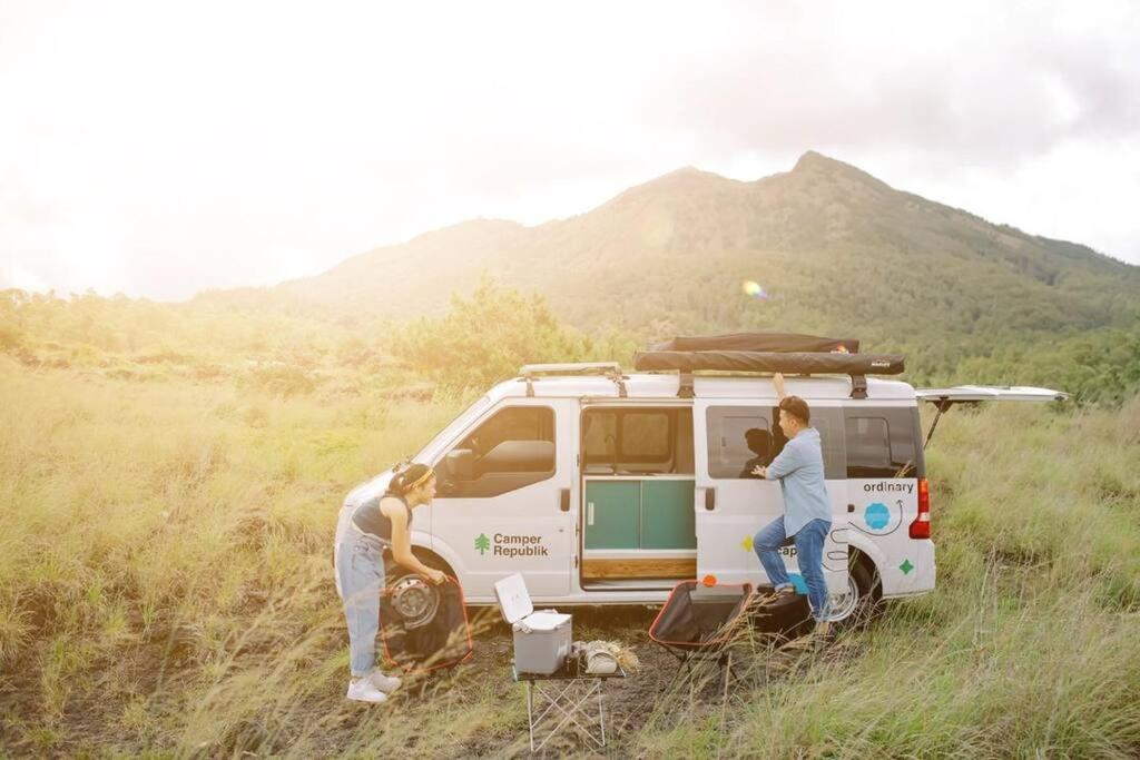 two women standing next to a van in a field at Campervan Bali Rental in Dalung