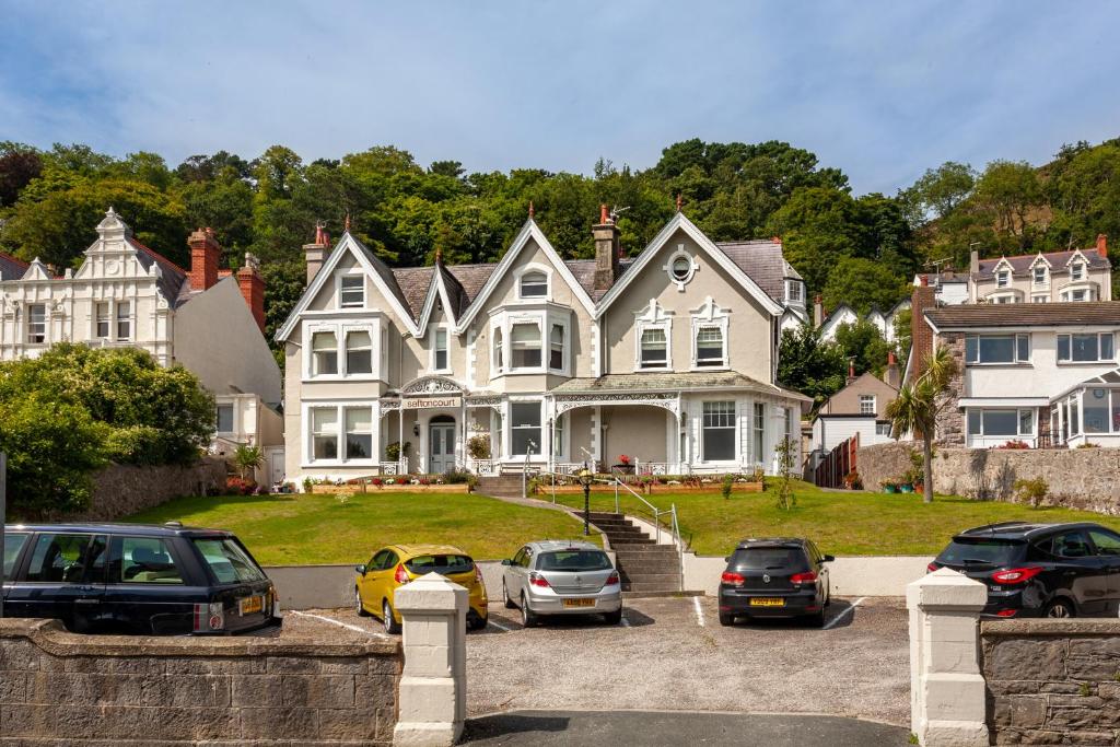 a large house with cars parked in a parking lot at Sefton Court in Llandudno