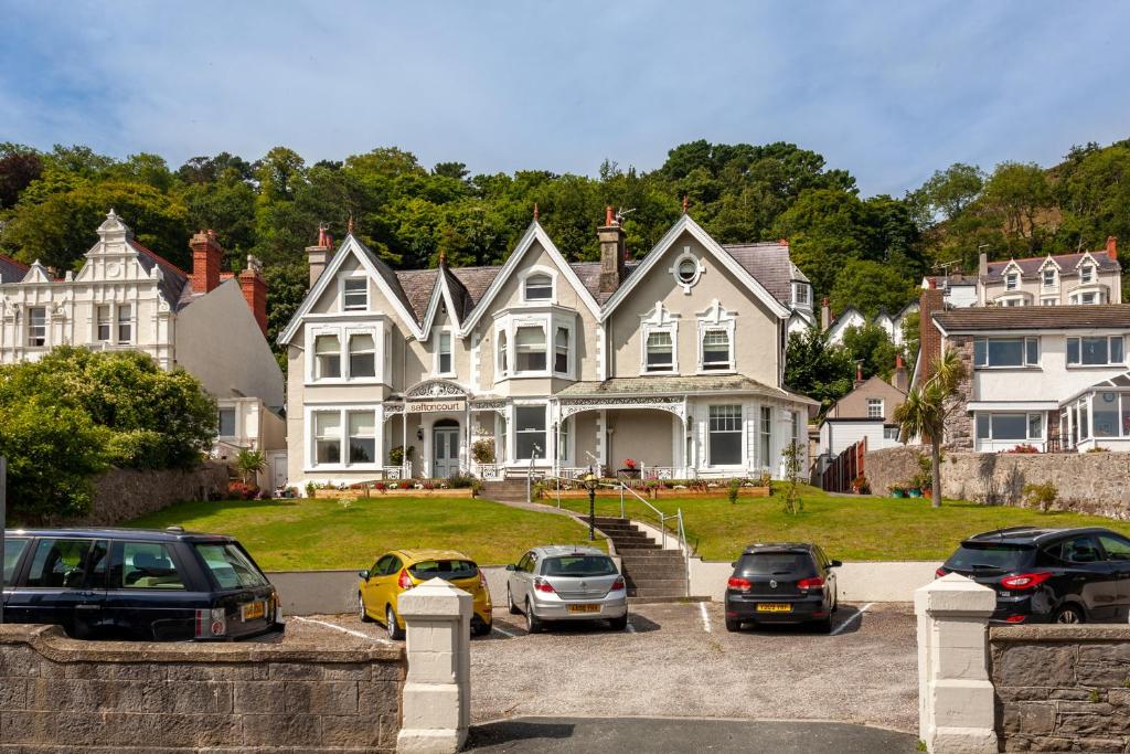 una casa grande con coches aparcados en un aparcamiento en Sefton Court en Llandudno