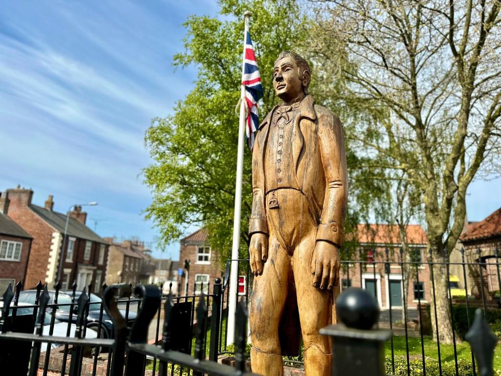 uma estátua de um homem segurando uma bandeira britânica em The Bradley em Market Weighton