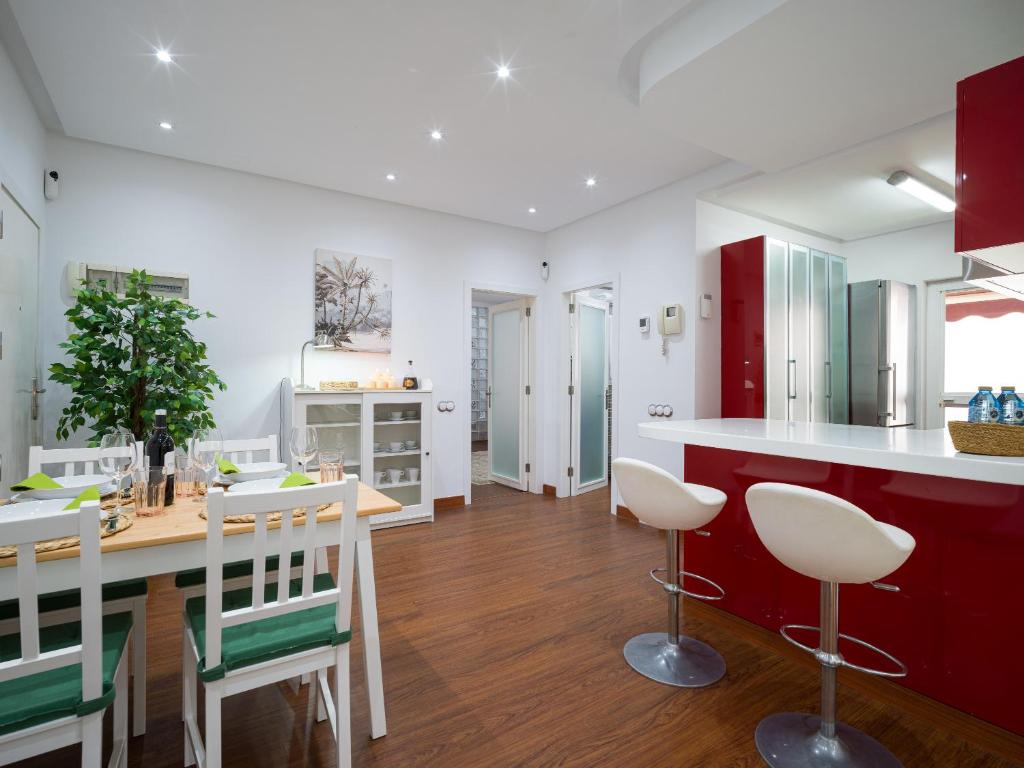 a kitchen with white and red cabinets and a wooden table at City Family Ciudad Jardín in Las Palmas de Gran Canaria