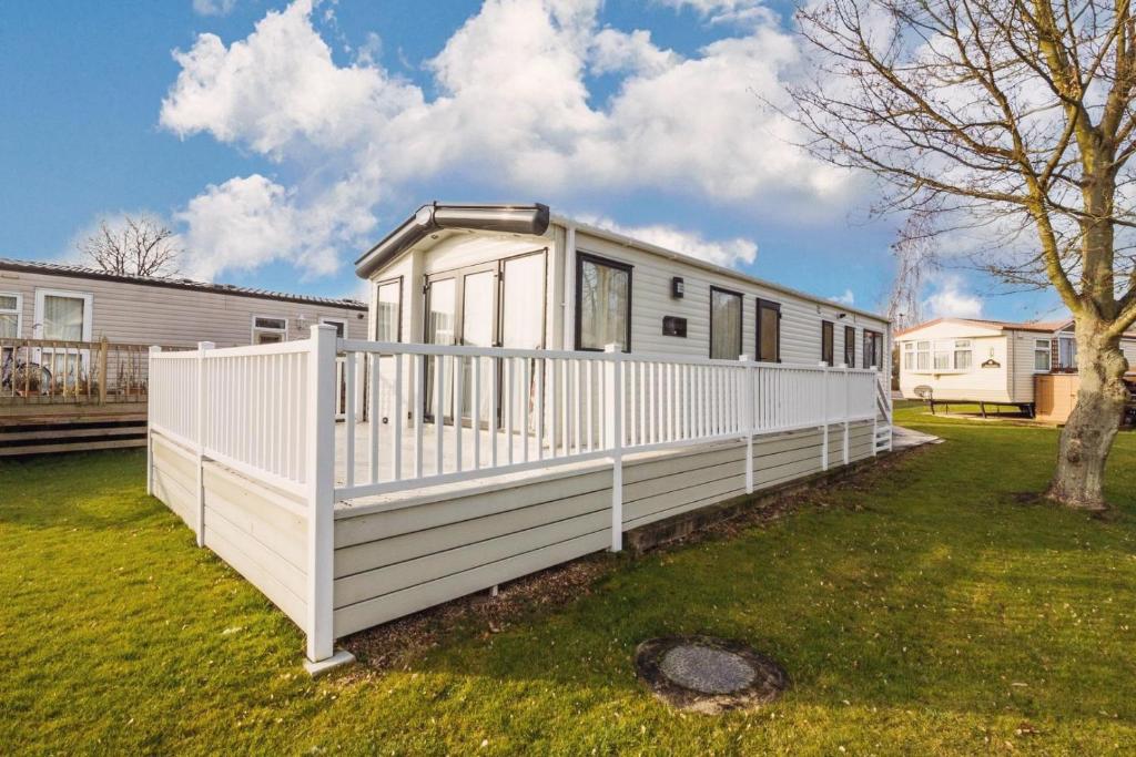 a white house with a fence in a yard at Lovely 6 Berth Caravan At Carlton Meres Holiday Park In Suffolk Ref 60021r in Saxmundham