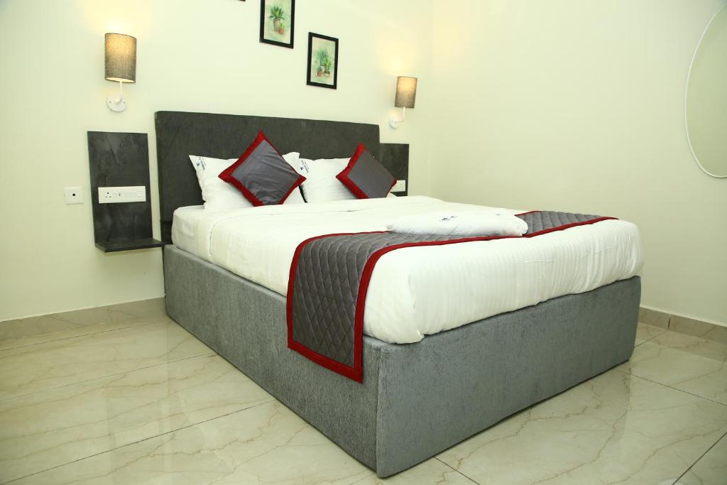 a bedroom with a large bed with white and red pillows at Seasons Stay in Vijayawāda