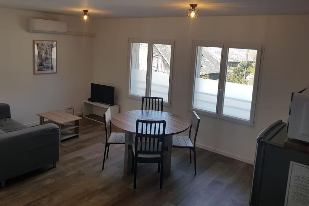 ein Wohnzimmer mit einem Tisch, Stühlen und einem TV in der Unterkunft Appartement T2 Saint Malo, Dinard, Dinan et Dol in Miniac-Morvan