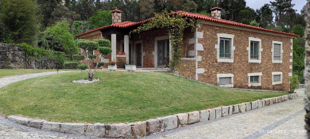een stenen huis met een grasveld ervoor bij Charme da montanha in Montaria