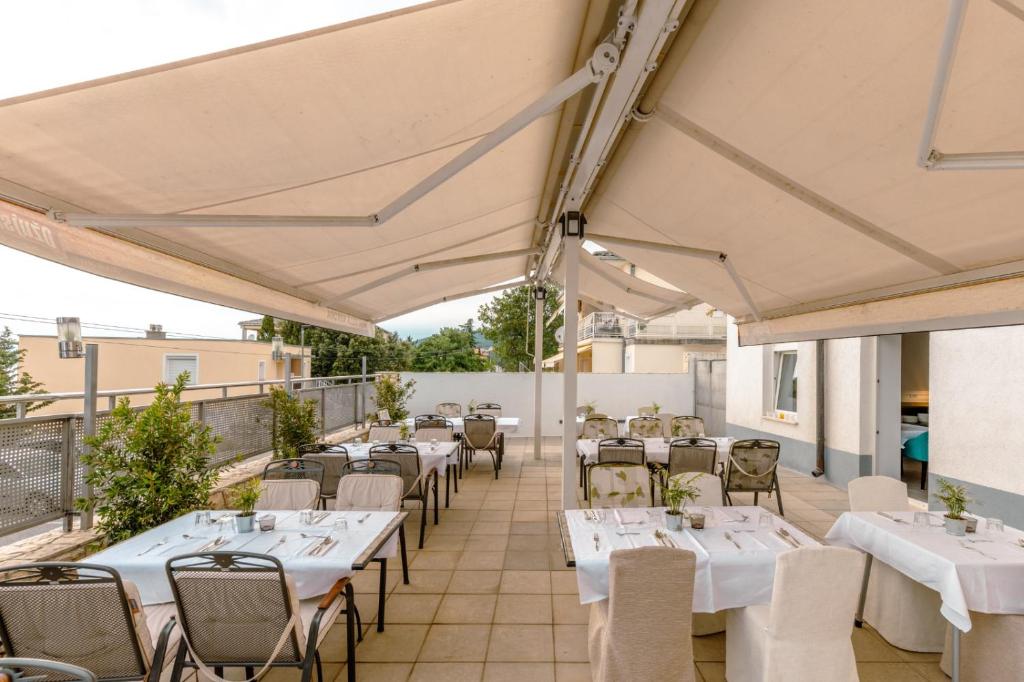 a restaurant with white tables and chairs on a balcony at Hotel Villa Aurora in Crikvenica
