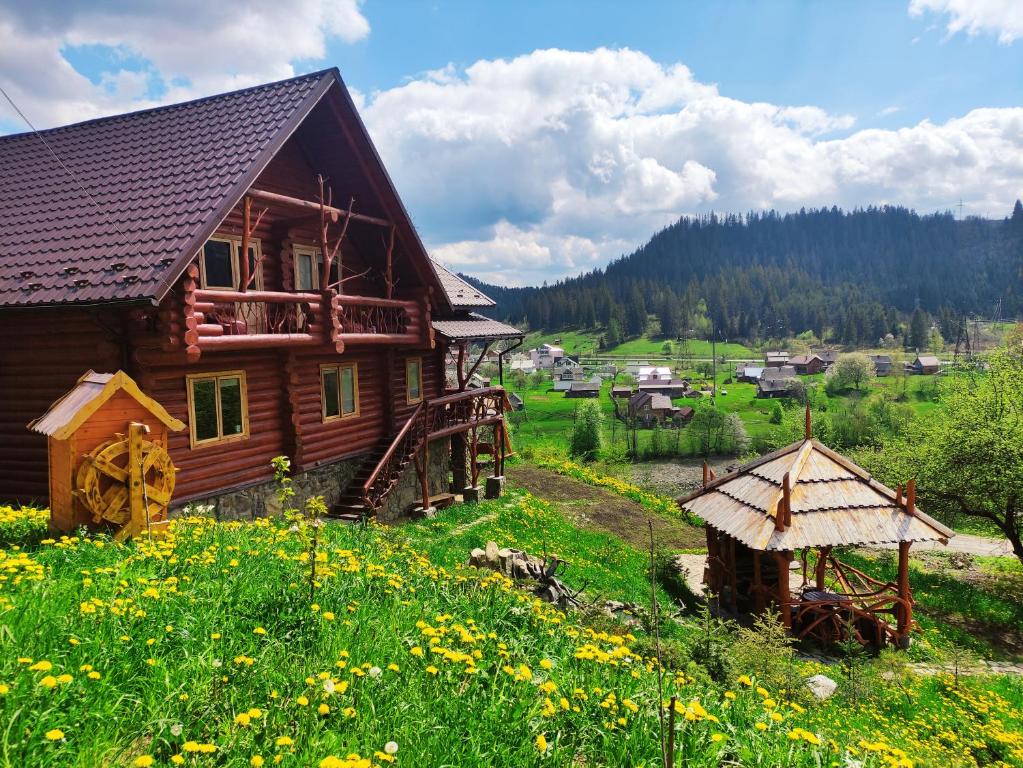 ein Holzhaus auf einem Blumenfeld in der Unterkunft Дерев'яний котедж "Казка" in Jaremtsche