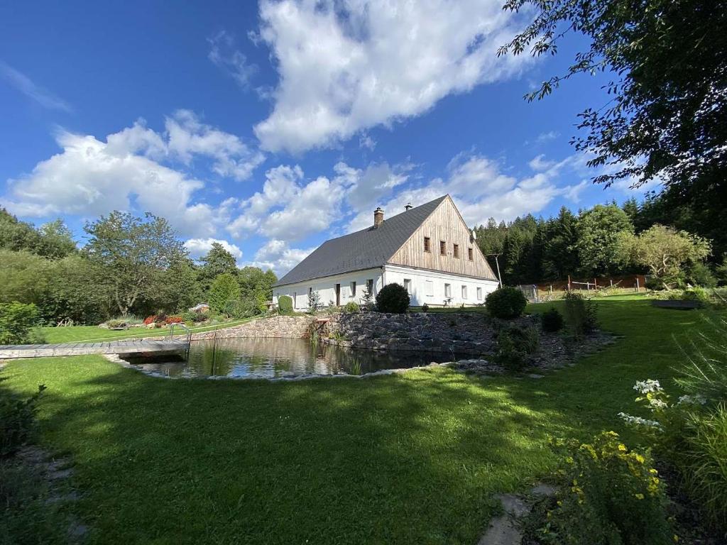 una gran casa blanca con un estanque frente a ella en Chalupa u dvou studánek, en Horní Orlice