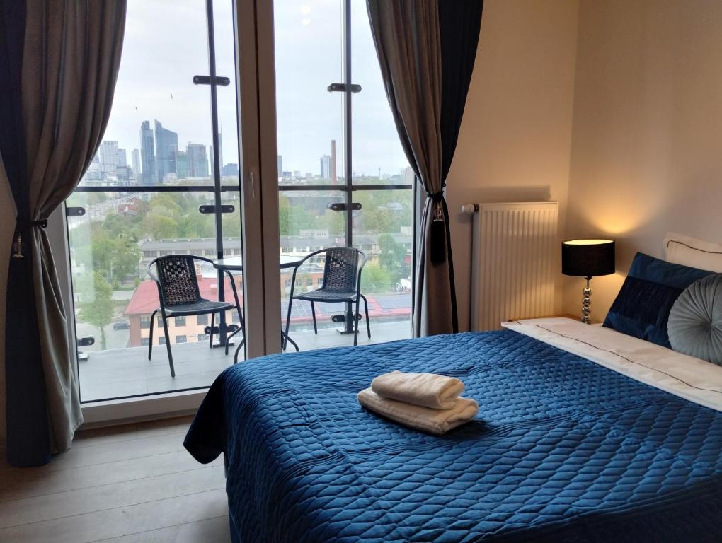 um quarto com uma cama azul e uma grande janela em Kasprzaka 29 Perfect Apart (L) em Varsóvia