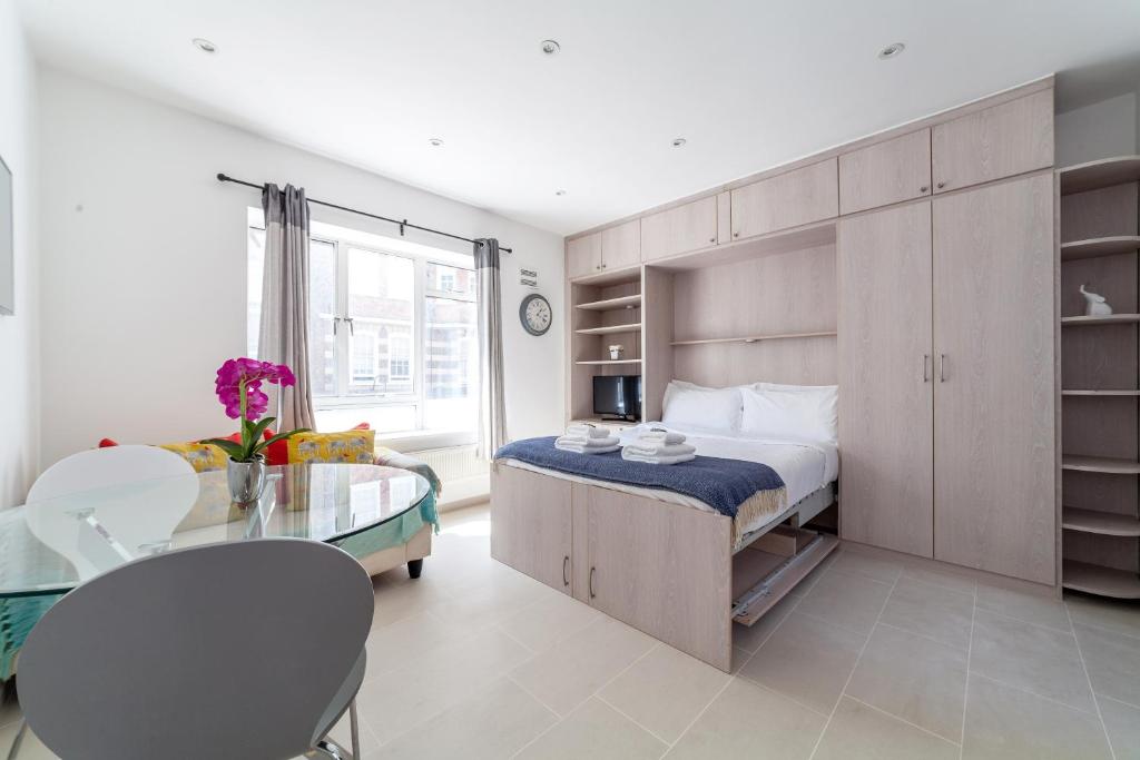 1 dormitorio con cama y mesa de cristal en Bright Studio Flat in the Heart of Marylebone en Londres
