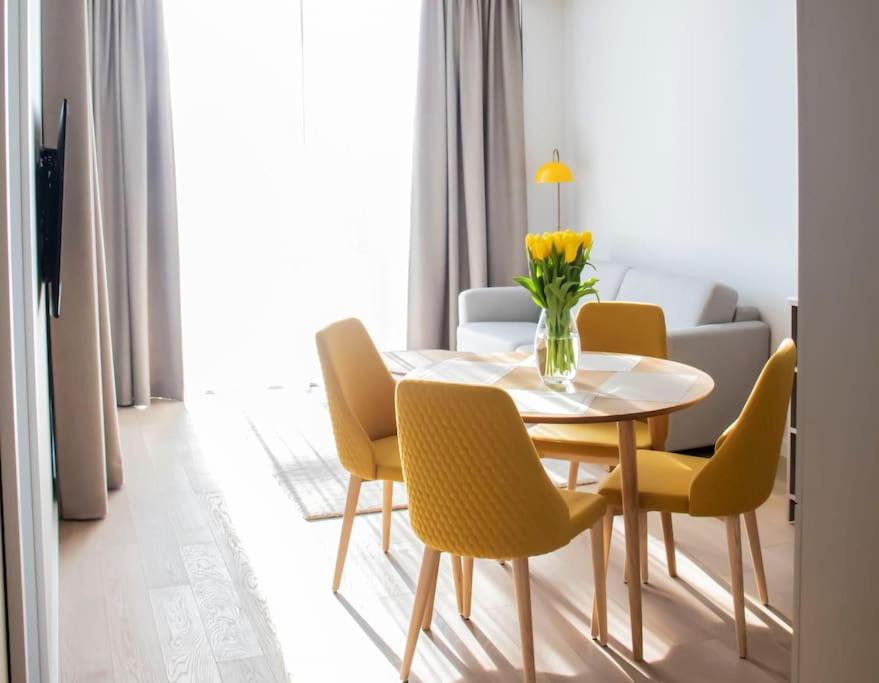 uma sala de jantar com uma mesa e cadeiras amarelas em Parko Aveniu Apartamentai em Birstonas