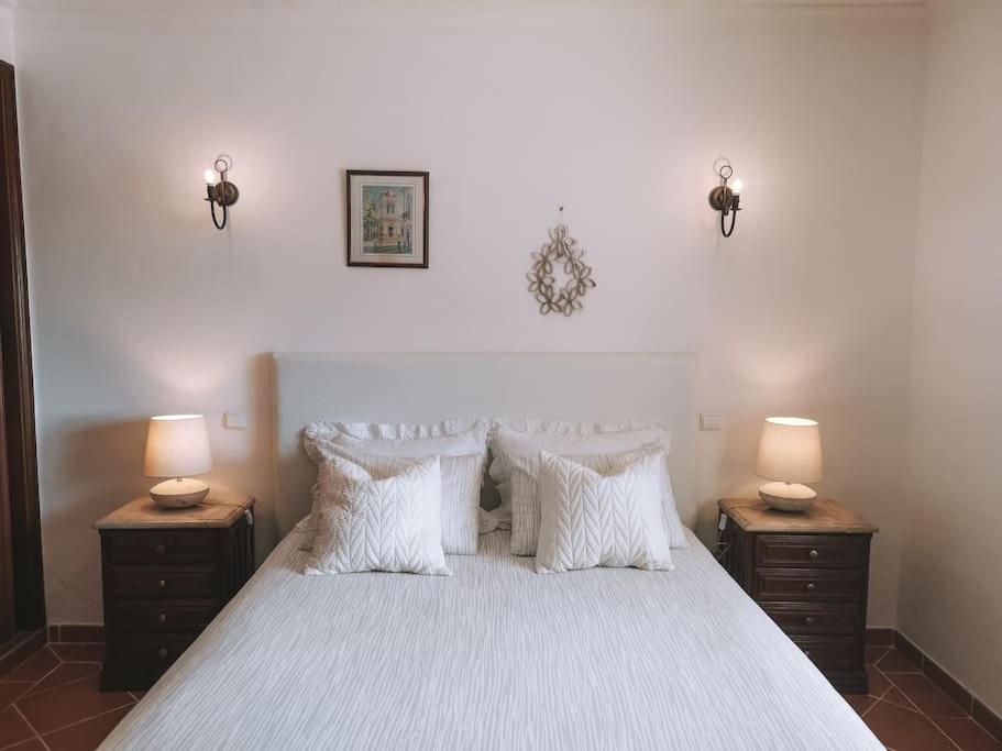 um quarto com uma cama com almofadas brancas e 2 candeeiros em Green Ville em Faro