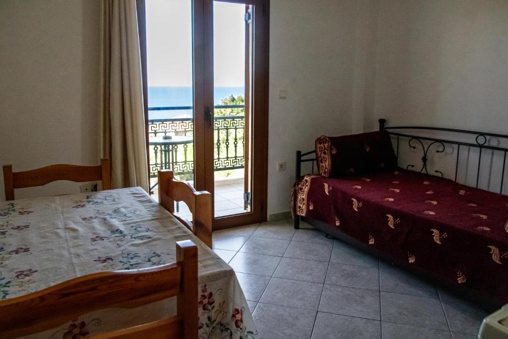 a bedroom with a bed and a table and a window at Ανεμώνη Apartments in Gialiskari
