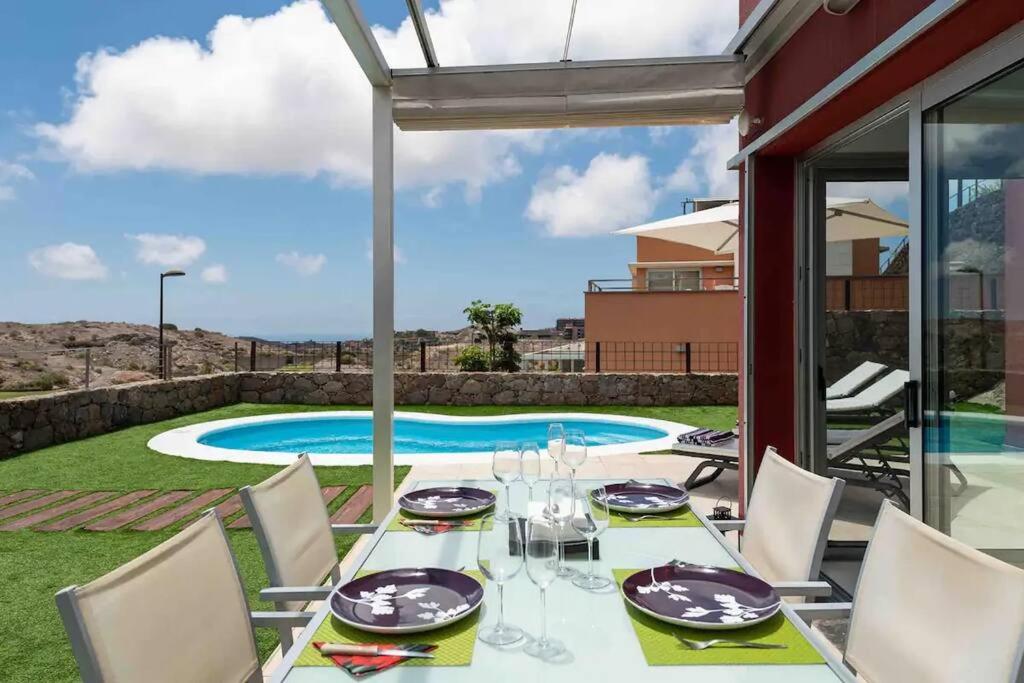 a dining table with chairs and a view of a pool at Sea View Villa Vista Golf in Salobre