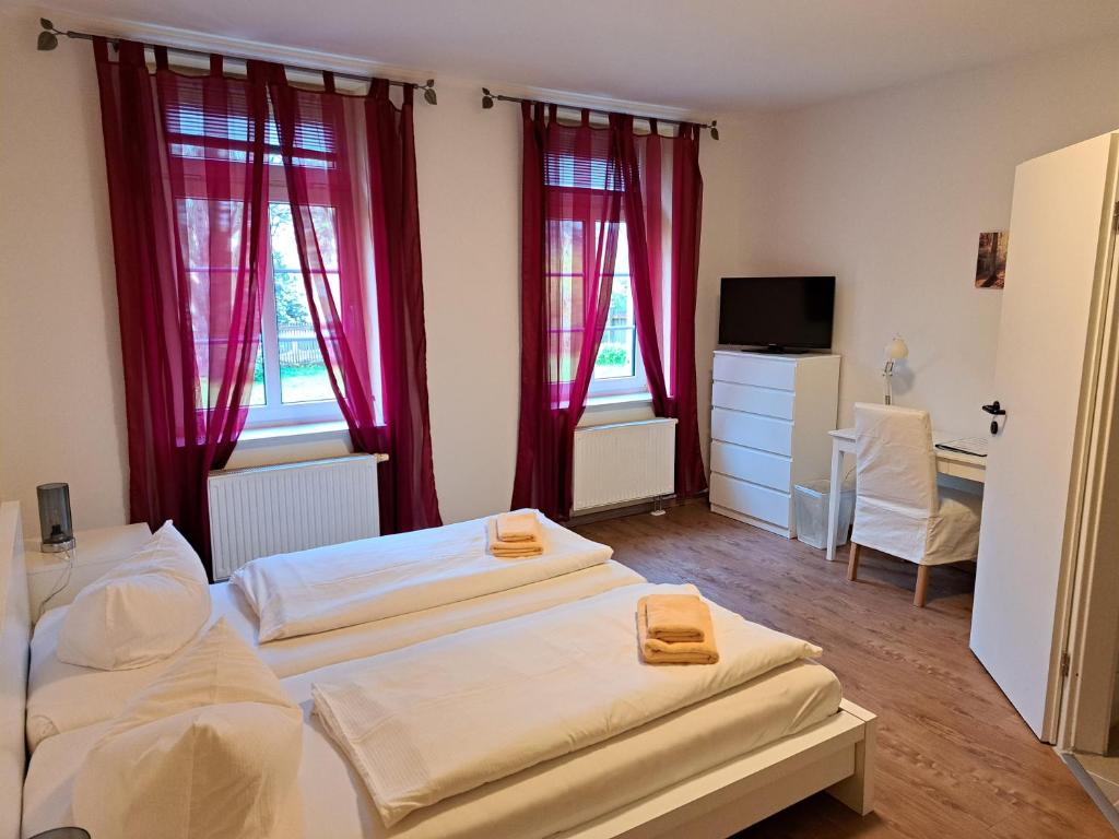 2 Betten in einem Zimmer mit roten Vorhängen in der Unterkunft Gästehaus Villa Seraphinum in Dresden