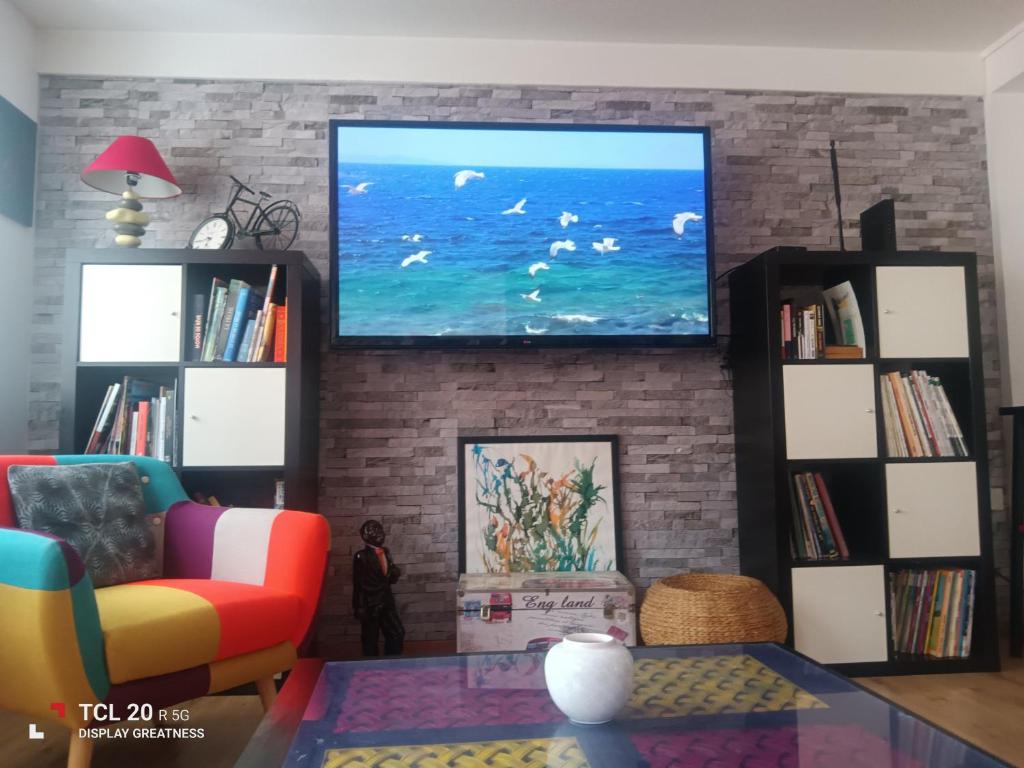 a living room with a large tv on a brick wall at sur ile du pollet in Dieppe