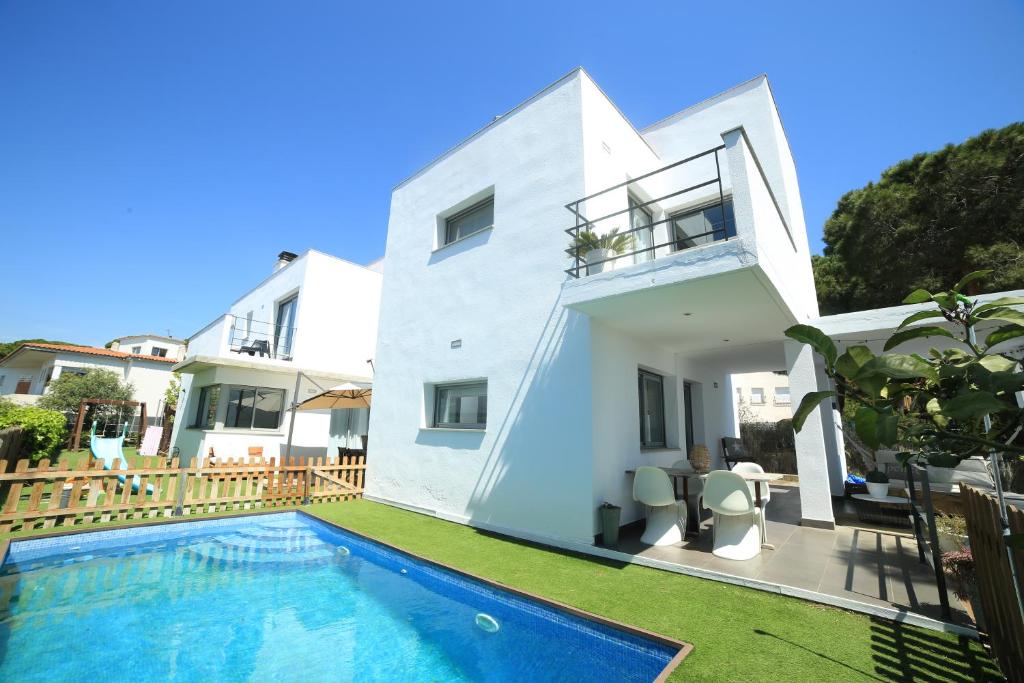 una casa blanca con piscina frente a ella en Relax con Piscina Privada y Vistas al Mar, en Sant Pol de Mar