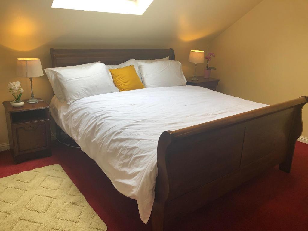 um quarto com uma cama grande com lençóis brancos e almofadas amarelas em Railway Avenue Rooms em Clifden