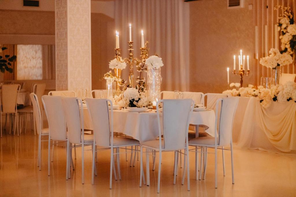a dining room with white tables and chairs and a chandelier at Svadbeni salon i prenoćište MILANOVIĆ in Nevesinje
