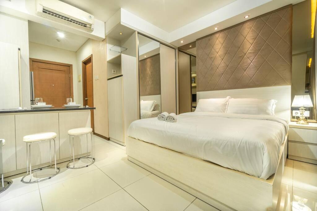 a bedroom with a large white bed and a kitchen at Modern & comfy studio in central Jakarta, SCBD in Jakarta