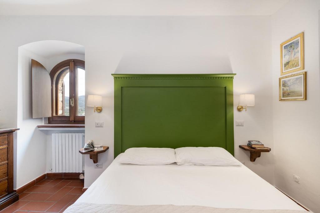 un letto con testiera verde in una stanza di Smeraldo a Spello