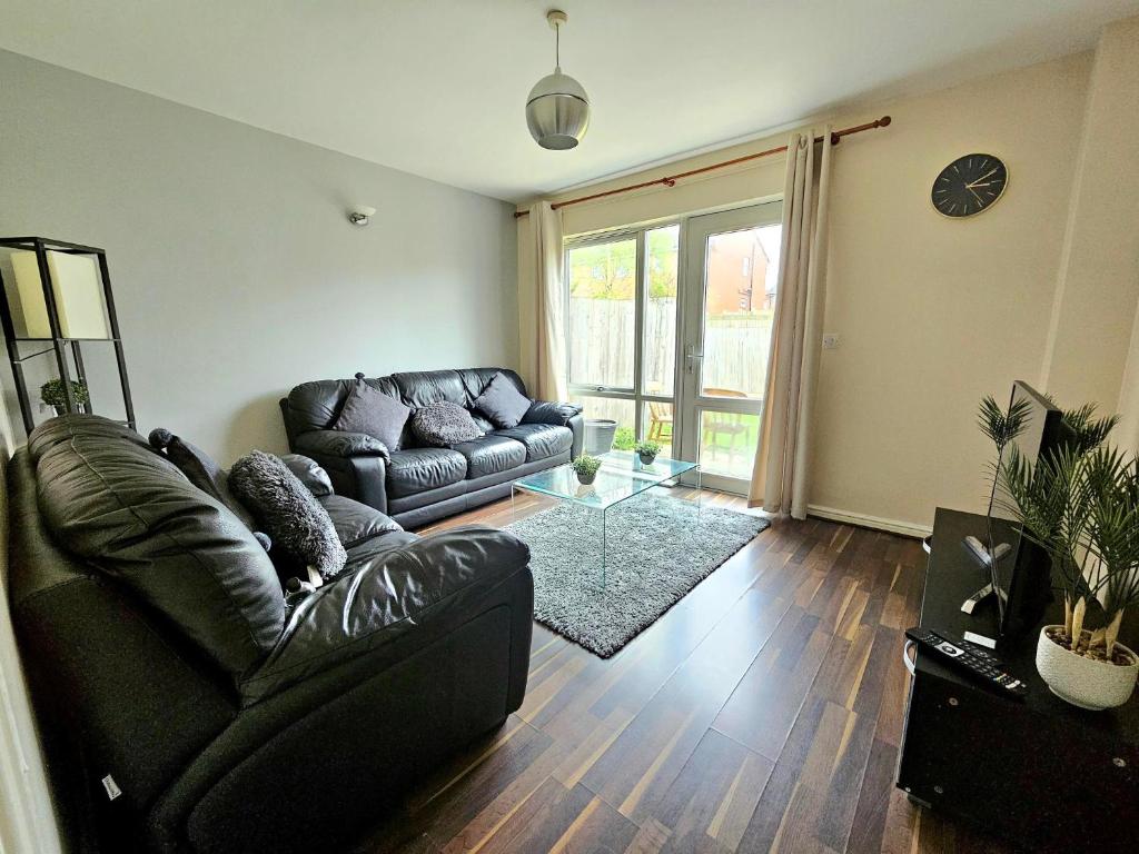 a living room with a leather couch and a glass table at Baltic Gem 4 Bedroom Townhouse with free parking in Liverpool