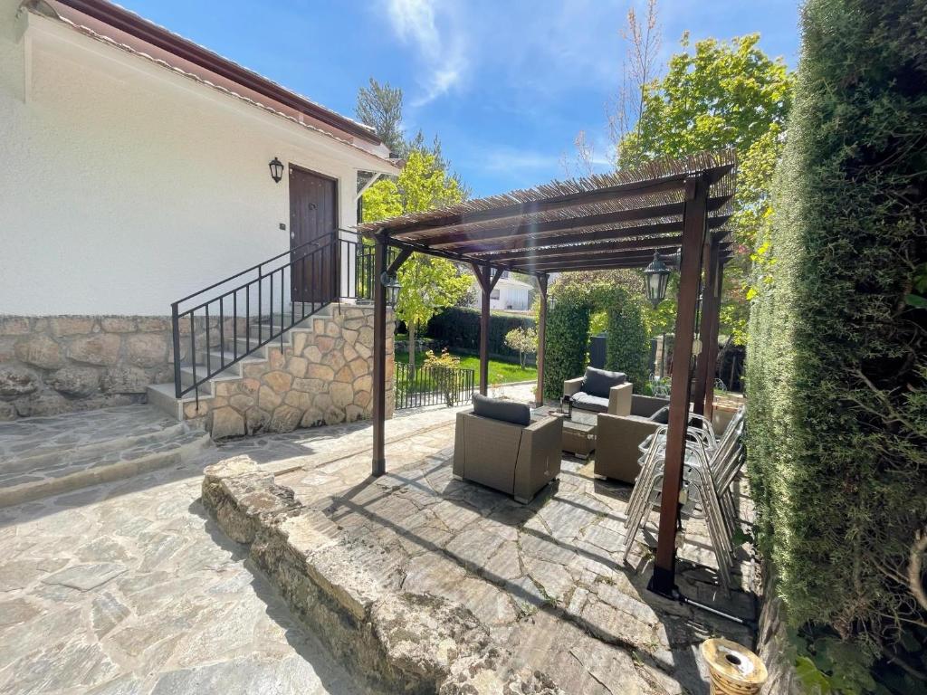 een patio met een pergola en meubilair in een tuin bij La Fontanilla en Estación de El Espinar in Segovia