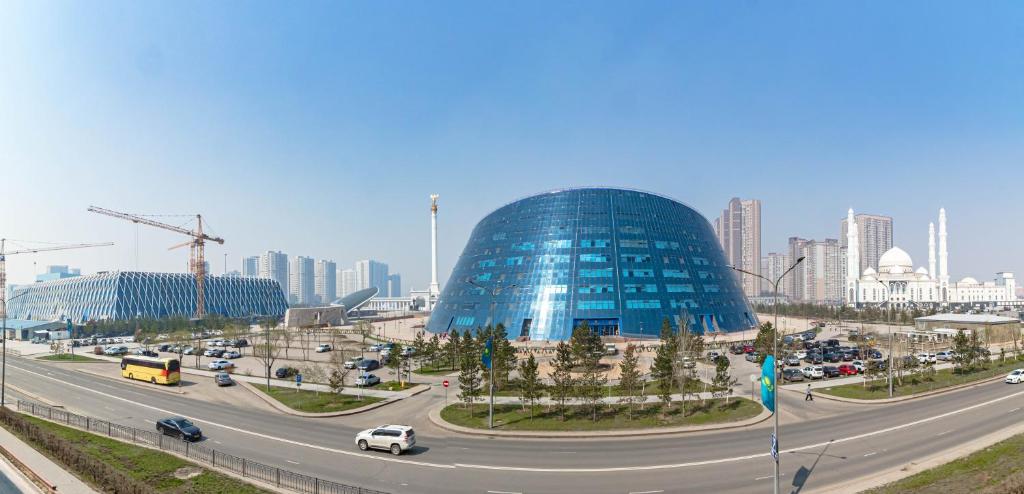 a large glass building in the middle of a highway at Жк Millennium Park, Большие Апартаменты на площади страны in Astana