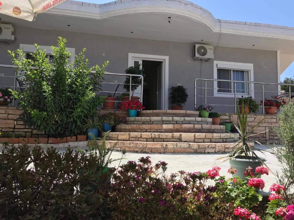 a house with stairs and potted plants and flowers at Nardi Guesthouse in Ksamil