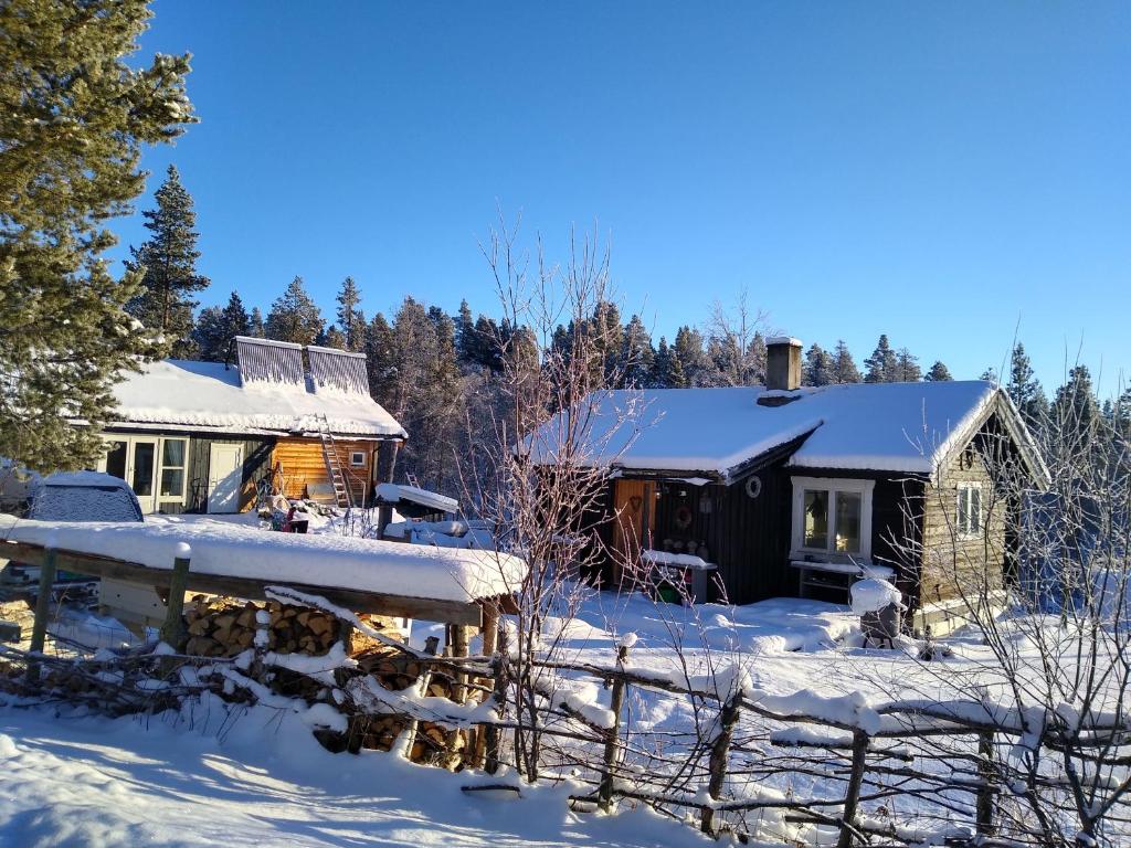 una cabaña de madera en la nieve con una valla en Furuly vakantiehuis en Vingelen