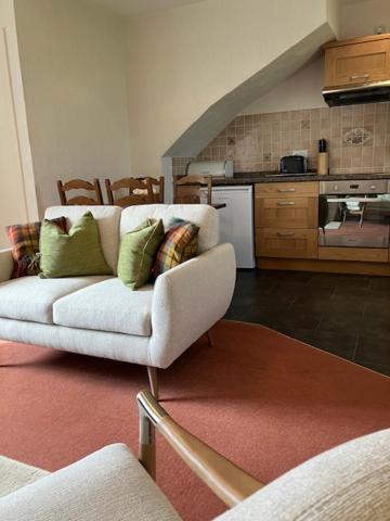 a living room with a white couch and a kitchen at Eastwood Cottage in Turriff