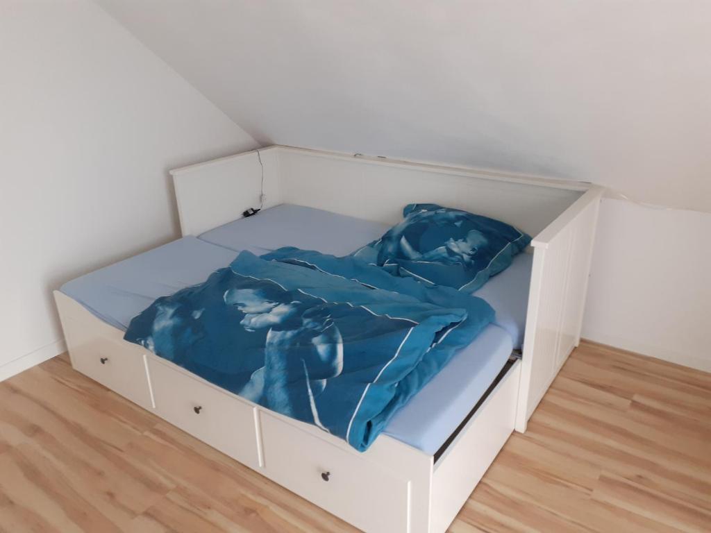 un letto bianco con lenzuola blu in una scatola di Schönes Zimmer in der Wetterau a Ranstadt