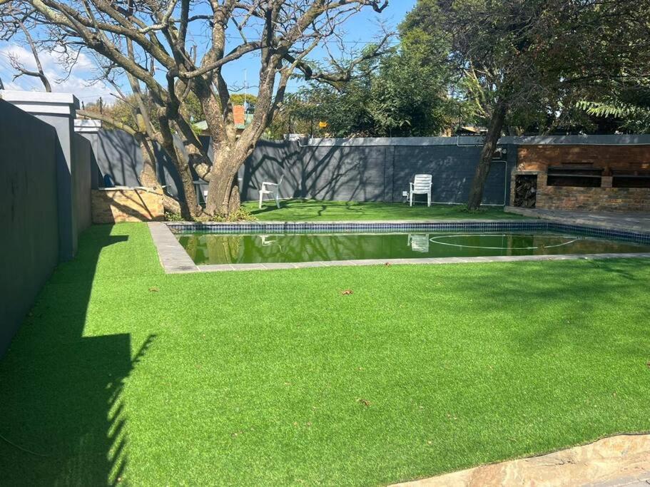 une cour avec de l'herbe verte et un bassin d'eau dans l'établissement Ubuntu Lifestyle Estate, à Krugersdorp