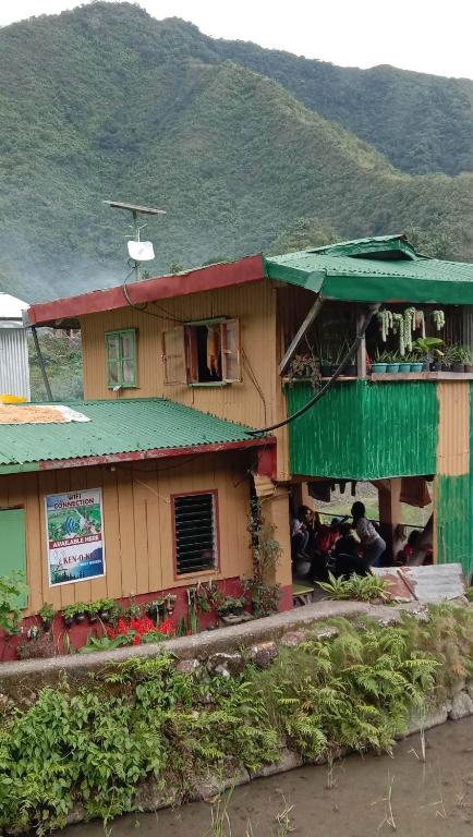 a house with people sitting outside of it at Batad Family Inn and Hidden Hut in Banaue