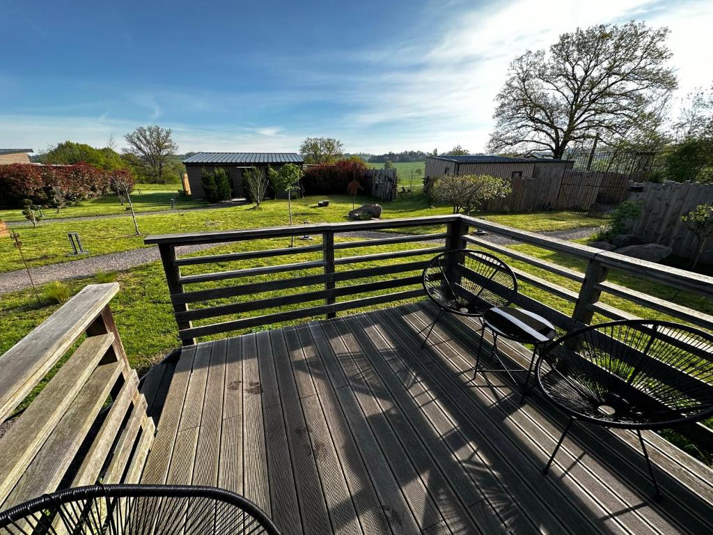 a bench sitting on a wooden deck with a fence at Le cottage in Jeanménil