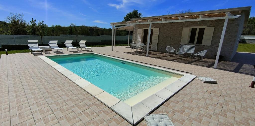 a swimming pool with chairs and a house at Janus Casa nel Verde - Relax Pool & Spa in Giano Vetusto