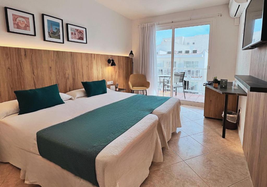 a hotel room with a large bed and a balcony at Alfons Hotel in Ciutadella