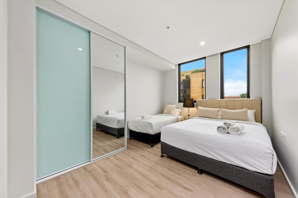een slaapkamer met 2 bedden en een groot raam bij Elegant and Modern Style Apartments in Dulwich hill in Sydney