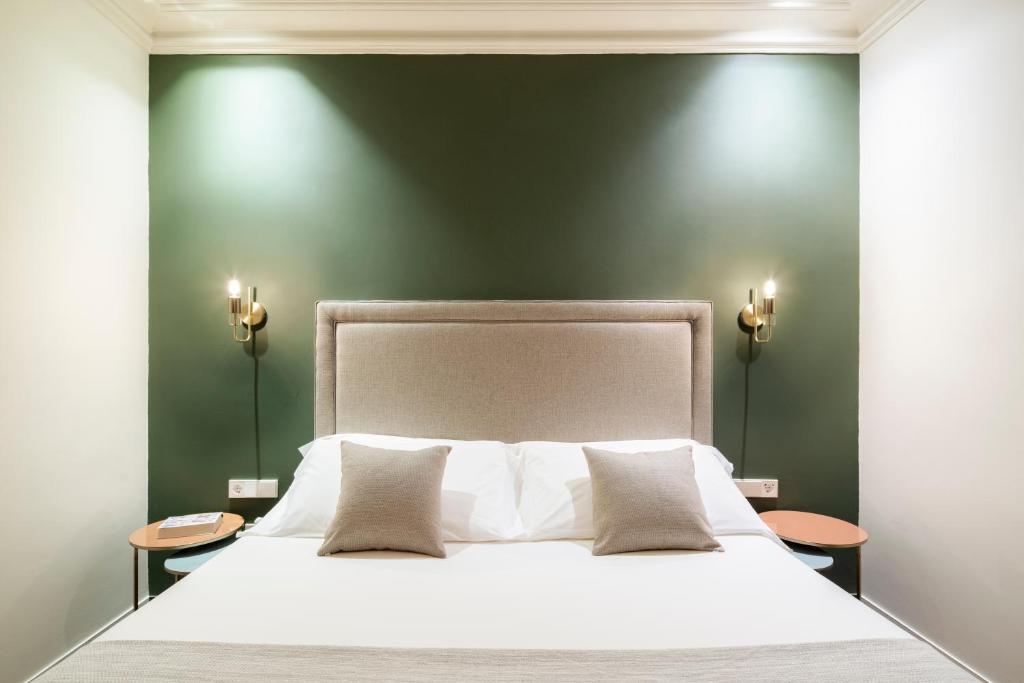 a bedroom with a white bed with a green wall at H Regas Adults Only in Barcelona
