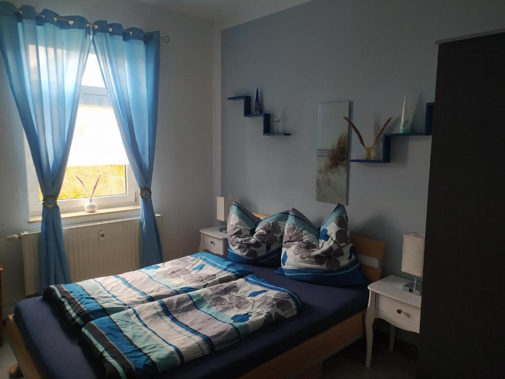 a bedroom with a bed with blue curtains and a window at Ferienwohnung am Tierpark Weißwasser in Weißwasser