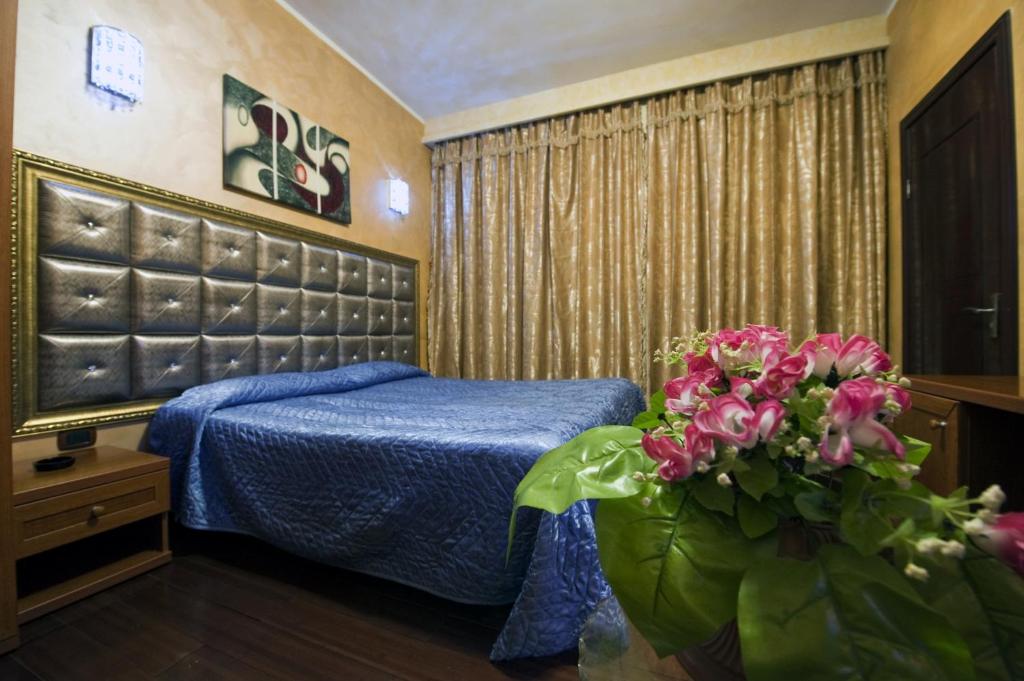 a bedroom with a blue bed and flowers in it at Hotel Bengasi in Moncalieri