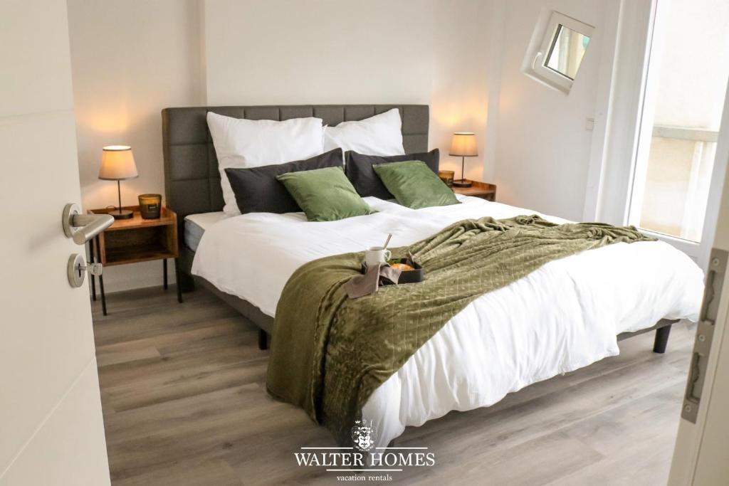 een slaapkamer met een bed met witte lakens en groene kussens bij Fachwerkcharme: Wohnen in großer Maisonettwohnung in Villingen-Schwenningen